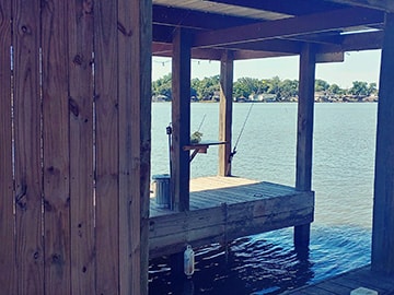 Covered fishing dock with rods over Lake Conroe at Venice On The Lake